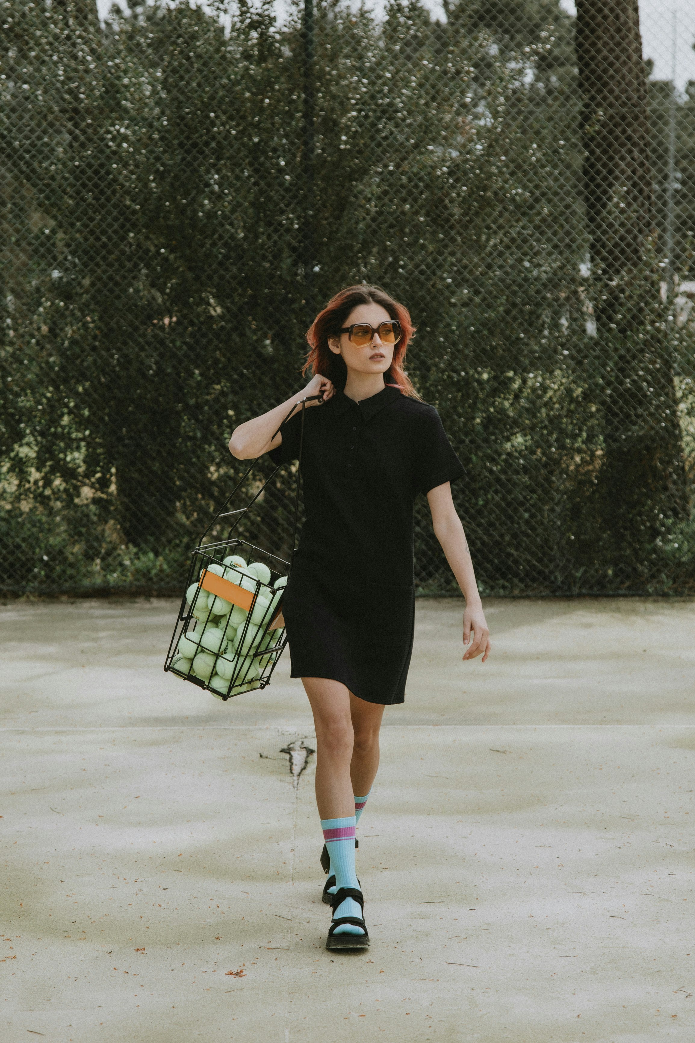 woman in black long sleeve dress and blue denim daisy dukes standing on white sand during